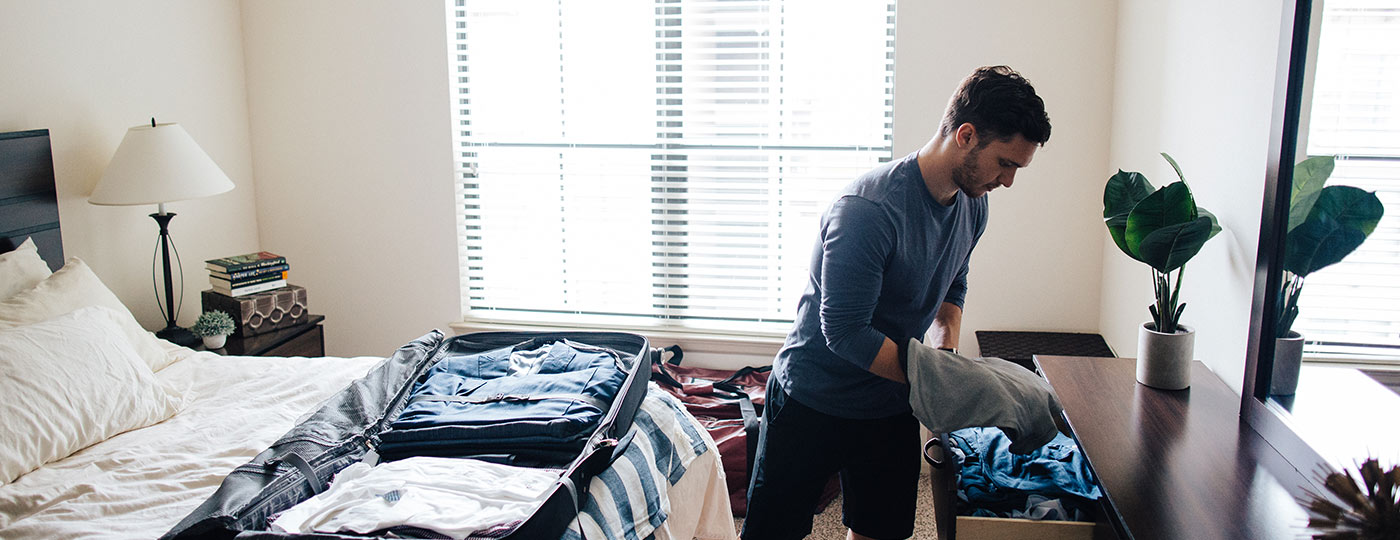 Commuter unpacking suitcase in a bedroom with CORT furniture rental